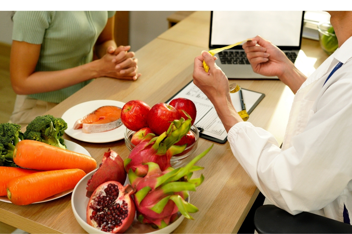 nutrition table with healthy foods. You can see a patients hands and the nutrition coach's hands and computer.