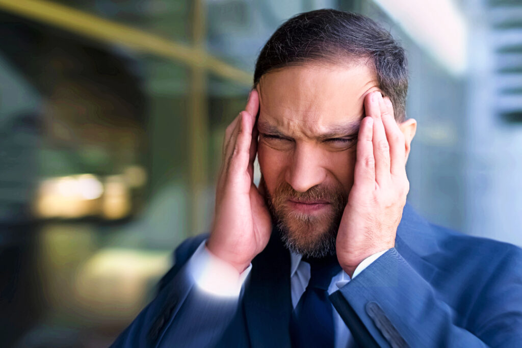 Man rubbing the temples of his head with his hands with his eyes closed tight.